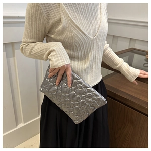Silver quilted heart pouch shown in hand to highlight metallic texture and size