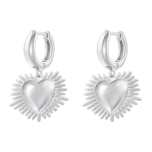 Macro view of silver heart earrings with radial textures and polished metal finish