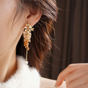 Detail of floral earring with crystal beads and white cube pendant worn by a model