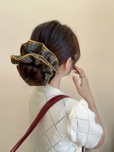 Detail showing oversized plaid scrunchie with yellow piping on a bun hairstyle