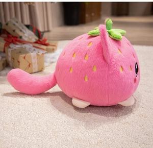 Close-up of cute strawberry cat plush toy with pink fur and embroidered seeds on carpet