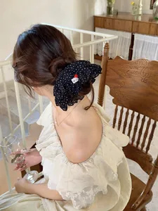 Close-up of black polka dot scrunchie with red heart hand made tag on model's hair