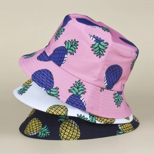 Détail de trois bobs réversibles avec imprimés ananas éclatants en plusieurs coloris variés