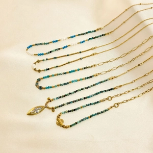 Detail of African pine stone necklace with gold-plated leaf pendant and pearls on silk