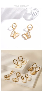 Detail display of gold-plated butterfly and shell pendant earrings on marble background