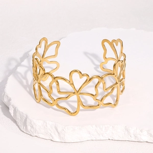 Bracelet jonc ouvert à fleurs creuses et cœurs en acier doré 18 carats sur pierre