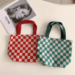 Detail of red and green checkerboard corduroy handbags with metal snap and ribbon handles