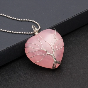 Pink heart crystal necklace with silver tree of life wire wrapping on black background