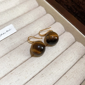 Detailed shot of golden tiger eye beaded earrings displayed in a luxury jewelry box