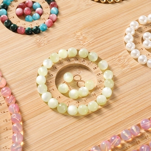 Detailed bamboo bead board showing scale markings with assorted colorful gemstone beads
