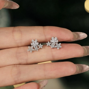 Sparkling S925 sterling silver snowflake stud earrings with crystals on a fingertip