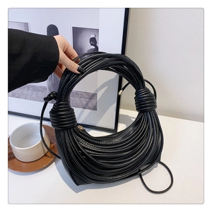 Detail of black synthetic leather shoulder bag with unique layered rope design and side knot