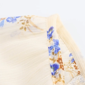 Dettaglio del tessuto in chiffon floreale con base beige e motivi floreali blu e marroni