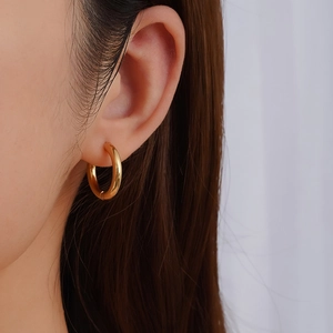 Minimalist gold stainless steel hoop earring shown on ear for a stylish unisex look
