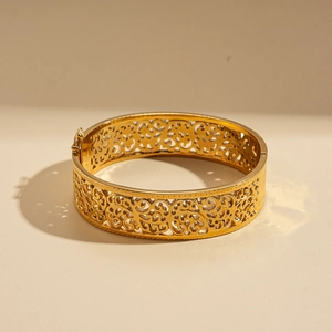 Close-up of golden stainless steel bangle with intricate vintage hollow geometric patterns
