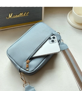 Detail of light blue pebble leather crossbody bag with wide strap and phone storage