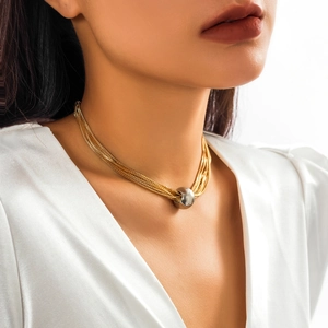 Detail shot of multi-layered gold chain necklace featuring a silver bead pendant on neck