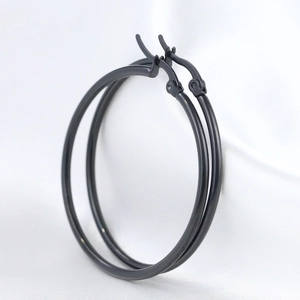 Macro shot of 50mm black stainless steel hoop earrings on a white satin fabric background