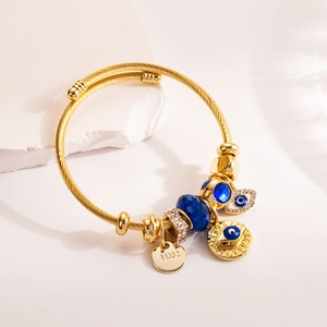 Gold twist bangle with blue faceted beads and sparkling evil eye pendant on stone