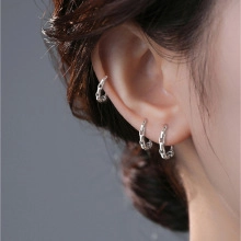 Macro detail of silver chain texture earrings and ear cuff set worn on a model