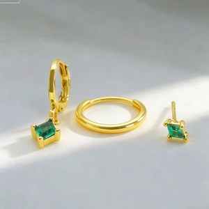 Macro shot of gold hoop and stud earrings set with square green zircon crystals