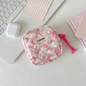 Flat-lay of floral quilted sanitary bag on desk with laptop and lifestyle props