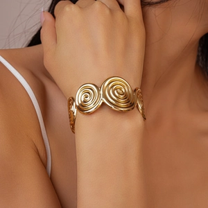 Detail of bohemian gold spiral texture cuff bracelet with metallic relief patterns