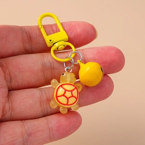 Detailed close-up of a resin turtle keychain with a yellow bell and gold-tone clasp
