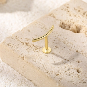 Macro detail of a golden S925 sterling silver butterfly bar piercing earring on stone