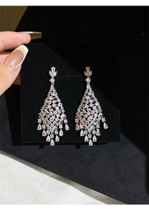 Macro shot of silver tassel earrings with sparkling zircon teardrop pendants on black card