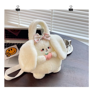 Close-up of plush rabbit bag with pink plaid bow and peach charm on a wooden table