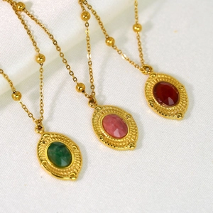 Macro shot of 14K gold beaded necklaces with oval green, pink, and red natural stones