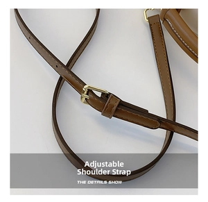 Gros plan d'une bandoulière réglable en cuir marron avec boucle en métal doré poli