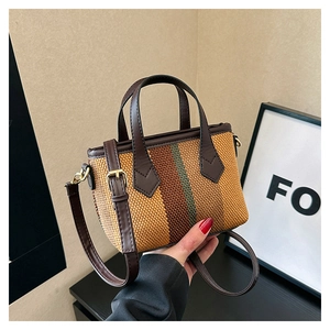 Close-up of small striped woven canvas bag with brown leather handle and gold hardware