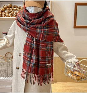 Detailed view of thick red plaid scarf with classic tassels and minimalist woven label