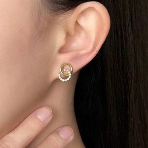 Detail of elegant intertwined gold and zircon double loop earrings worn by a model