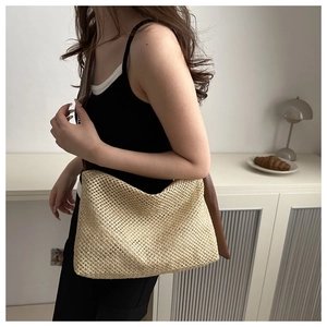 Detail of woven straw tote bag with brown leather strap and intricate mesh texture