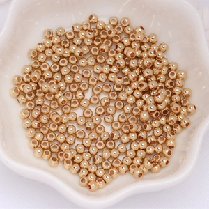 Macro shot of 14k gold-filled round beads with smooth metallic finish in a white bowl