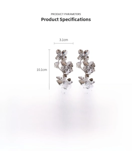Detailed view of long silver floral earrings with pearls and sequins measuring 10.1x3.1cm