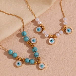 Detail of 18K gold-plated stainless steel necklaces with turquoise beads and evil eye charms
