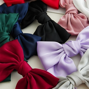 Flat lay close-up of colorful satin bow hair clips showing silky texture and various colors