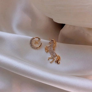 Macro view of gold asymmetric earrings with moon star and unicorn crystal patterns
