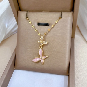 Detailed macro view of a gold-plated double butterfly pendant with pink enamel and crystals