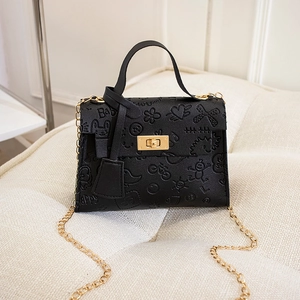 Close-up of black fashion handbag with cartoon embossing and gold twist lock