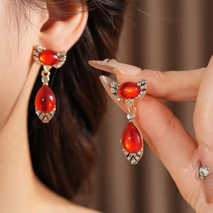 Detail of vintage gold bow earrings with oval red gemstone and sparkling rhinestones