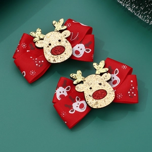 Detail of red Christmas bow hair clips with gold glitter reindeer and snowflake patterns
