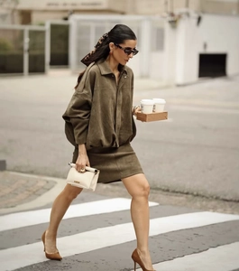 Street style shot of dark olive green suede jacket and matching skirt ensemble