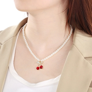 Detail of red cherry pendant necklace with crystals and pearls worn on a female model