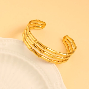 Macro detail of golden triple-layered bamboo joint cuff bracelet on white plate