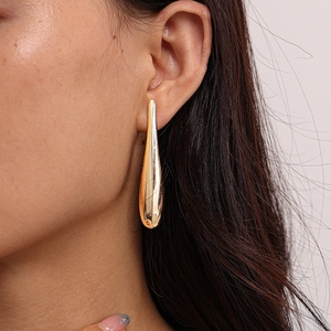 Close-up of elegant gold teardrop earrings with a smooth polished metallic finish